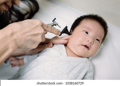 Cute Asian Newborn Baby Look Curious While Pediatrician Using An Otoscope To Check Her Ear Canal And Eardrum Membrane For A Monthly Check-up, Health Care Of Newborn Baby, Concept Newborn Baby Checkup.