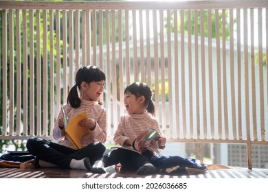 Cute Asian siblings girl reading a book at home.