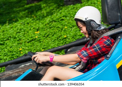 Cute Asian Thai Girl Is Driving Go-kart Car With Speed In A Playground Racing Track. Go Kart Is A Popular Leisure Motor Sports.