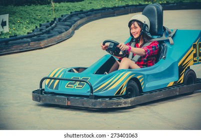 Cute Asian Thai Girl Is Driving Go-kart Car With Speed In A Playground Racing Track In Vintage Color. Go Kart Is A Popular Leisure Motor Sports.