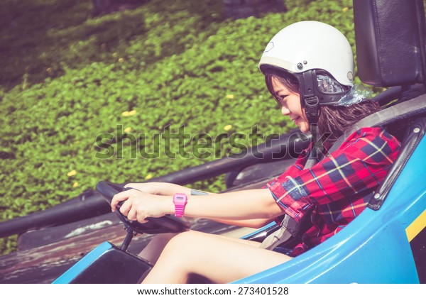 Cute Asian Thai teen girl is driving\
Go-kart car in playground with speed in retro\
color