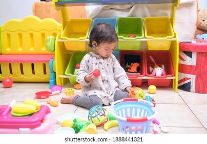 Cute Asian Toddler Girl Child Sitting On Floor Having Fun Playing Alone In Playroom At Home, Little Infant Girl Sitting W Posture Which Is Called W-sitting Knees Bent And Feet Positioned Outside Hips