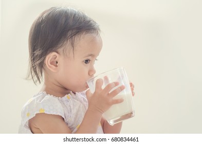 Cute Asian Toddler Girl Drinking Milk From A Big Glass