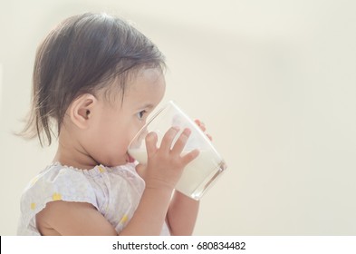 Cute Asian Toddler Girl Drinking Milk From A Big Glass