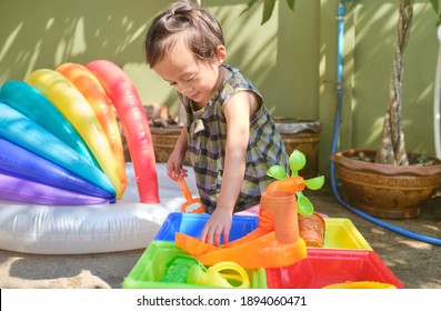 Cute Asian Toddler Girl Having Fun Playing With Water Table At Home, Wet Pouring Montessori Preschool Practical Life Activities, Fine Motor Skills Development, Stay Home Stay Safe Have Fun Concept