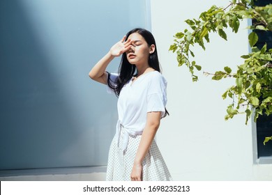 Cute asian woman facing the sun outdoor near plant branch.