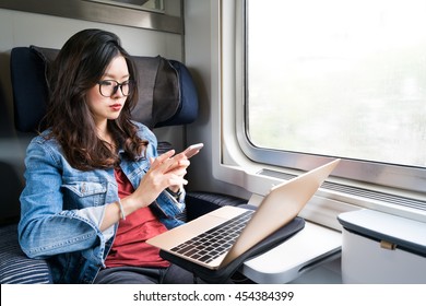 Cute Asian Woman Using Smartphone And Laptop On Train, Copy Space On Window, Business Travel Or Technology Concept