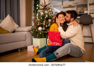 Cute attractive young couple exchanging presents enjoying their new year's party at home with their friend and family in front of a christmas tree laughing smiling. - Powered by Shutterstock