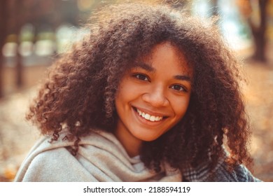 Cute Autumn Close Up Portrait Of Young Smiling Happy African American Woman With Curly Hair Enjoying Walk In Park In Fall Season. Outdoor Photo Of Pleased Black Girl With Eyes In Love With Life