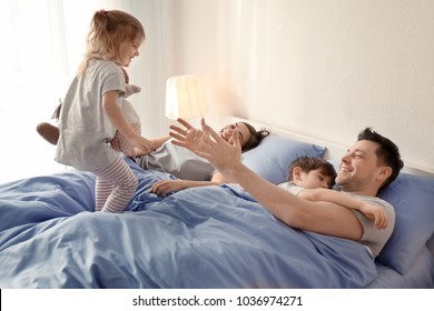 Cute awaken girl playing near sleeping family on bed at home - Powered by Shutterstock