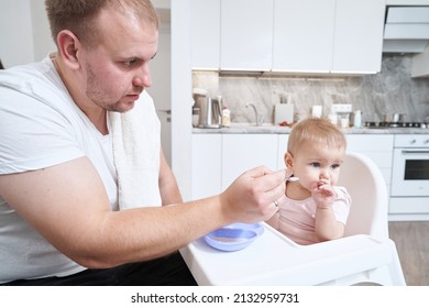 Cute Babe Sitting On The High Chair And Eating Breakfast With Father At Home