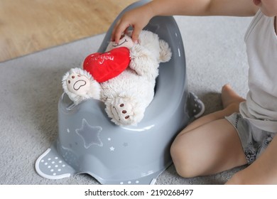 Cute Baby 2 Years Old Sits A Teddy Bear On The Potty. Pot For Children. Role Play Potty Training