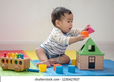 Cute Baby, Asian  Boy Sitting On A Playmate And Playing With Toy By Himself. Adorable Eight Month Old Child Happy Reach The Toy. Burred Or Out Of Focus. Education Can Start At Home Or Nursery Concept.