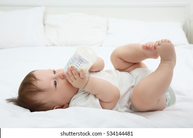 Cute baby with bottle on bed - Powered by Shutterstock