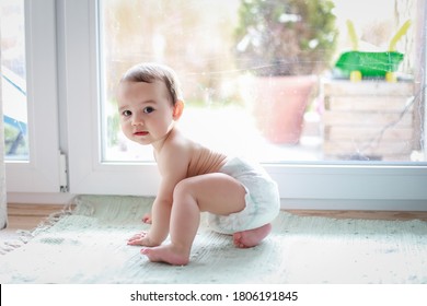 Cute Baby Boy In Diaper Crawling Next To Window Home. Mixed Race Asian-German Infant First Step Crawl. Happy Kid Learn And Play.