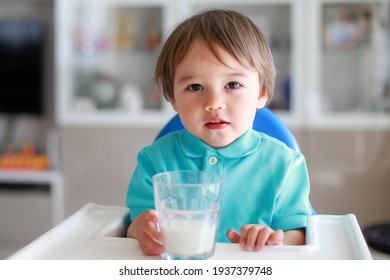 Cute Baby Boy Drinking Milk From Glass With Milk Mustache On High Chair At Home. Mixed Race Asian-German Infant Boy With Drink Healthy Nutrition.