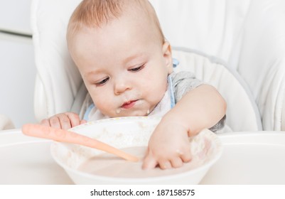 Cute Baby Boy Eating With Spoon And Hand On A White Background