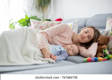 Cute baby boy and his mother, lying on the couch in living room, sleeping peacefully in the afternoon