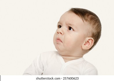 Cute baby boy looking up upset. Baby looking sad. Isolated on white.