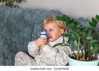 Cute Baby Boy Makes Inhalation With A Nebulizer Equipment. Sick Child Holding Inhalator In Hand And Breathes Through An Inhaler At Home. Physical Therapy For Cold, Flu And Bronchial Asthma