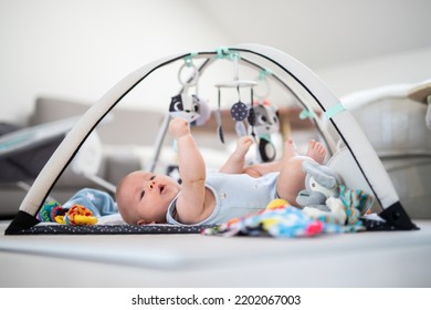 Cute baby boy playing with hanging toys arch on mat at home Baby activity and play center for early infant development. Baby playing at home - Shutterstock ID 2202067003