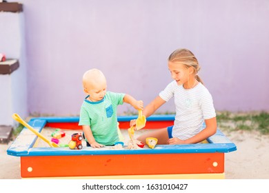 Cute Baby Boy Playing With His Sister With Toys In The Sandbox Outdoor