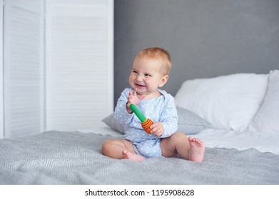 Cute baby boy playing with knitted toy on bed at home