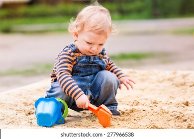 Cute Baby Boy Playing With Sand In A Sandbox