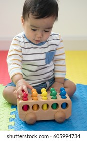 Cute Baby Boy Sitting On A Playmat And Playing With Toy By Himself. Adorable Eight Month Old Child Happy Reach The Toy,with Select Focus