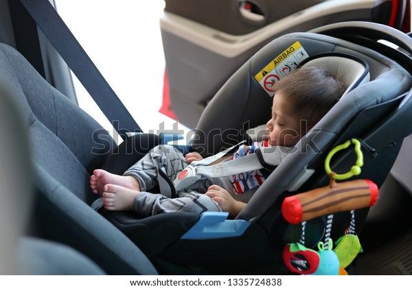 cute baby boy sleeping in car seat
safety belt lock protection drive road trip
travel