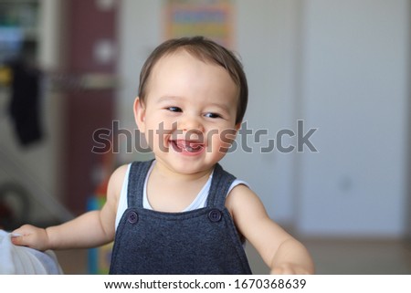 Cute baby boy smiling with first milk teeth. Mixed race Asian-German infant about 9-10 months old laugh face. Healthy newborn child.