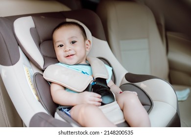 Cute baby boy smiling in safety car seat. Child transportation safety concept.
