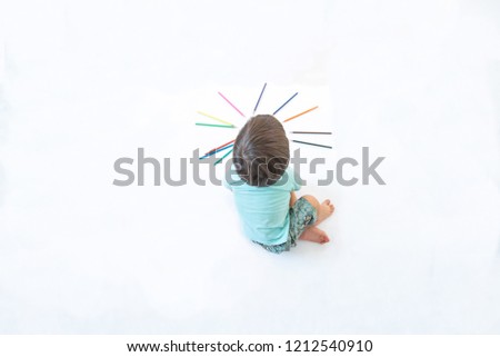 Cute baby boy toddler - drawing on white paper with colored pencils