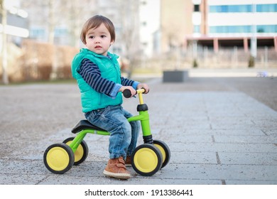 Cute Baby Boy Wearing Blue Jacket And Jeans Playing With Balance Bike On Outdoor Background. Happy Mixed Race Asian-German Child Play Outside.
