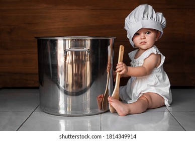 cute baby in the chef hat with a spoon and the large saucepan