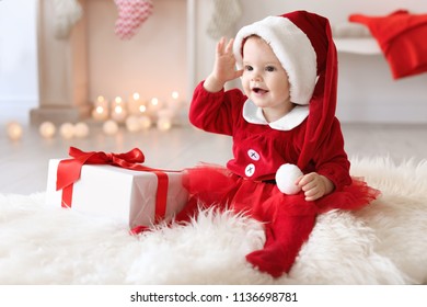 Cute Baby In Christmas Costume And Gift Box On Floor At Home