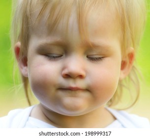 Cute Baby With Closed Eyes On Green Background.