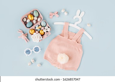 Cute Baby Costume Easter Bunny. Knitted Bodysuit With Fluffy Tail Bunny, Easter Eggs And Candy On Blue Background. Holiday Concept. Flat Lay, Top View