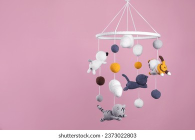 Cute baby crib mobile on pink background. Space for text