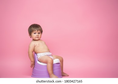 Cute Baby In A Diaper Sitting On A Potty. Toilet And Potty Training. A Small Child Gets Used To A Useful Skill. Hygiene.Baby Sitting On A Potty Toilet Stool Potty