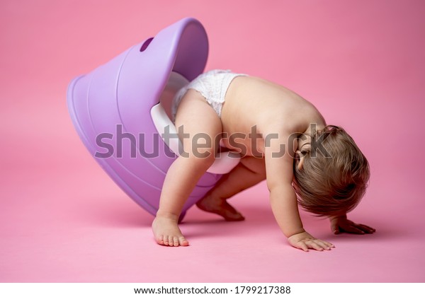 Cute baby in a diaper sitting on\
a potty. Toilet and potty training. A small child gets used to a\
useful skill. Hygiene.Baby sitting on a potty toilet stool\
potty