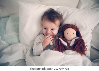 Cute Baby With A Doll With A Nebulizer Mask, A Sick Child In Bed, Bed Rest During Illness.