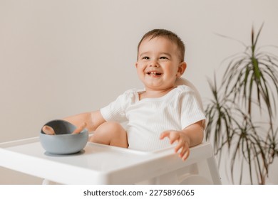 cute baby eats in a high chair made of silicone baby dishes. Baby food, space for text - Powered by Shutterstock
