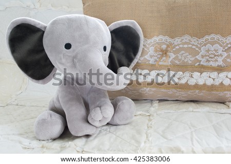 Cute Baby Elephant Stuffed Animal on White Quilt with Burlap