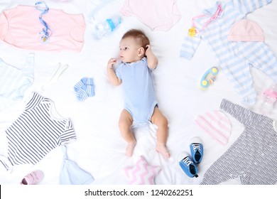 Cute Baby With Fashion Clothes Lying On White Bed