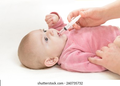 Cute baby gets medicine with a syringe in his mouth