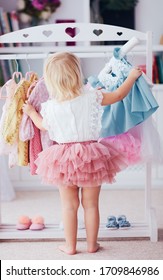 cute baby girl choosing the dresses in a wardrobe