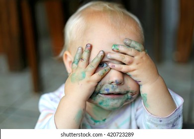 Cute Baby Girl Covering Her Messy, Painted Face With Her Dirty Hands