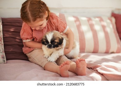 cute baby girl cuddling with puppy dog on summer patio at home