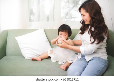 Cute Baby Girl Drinking Milk At Home With Her Mom.